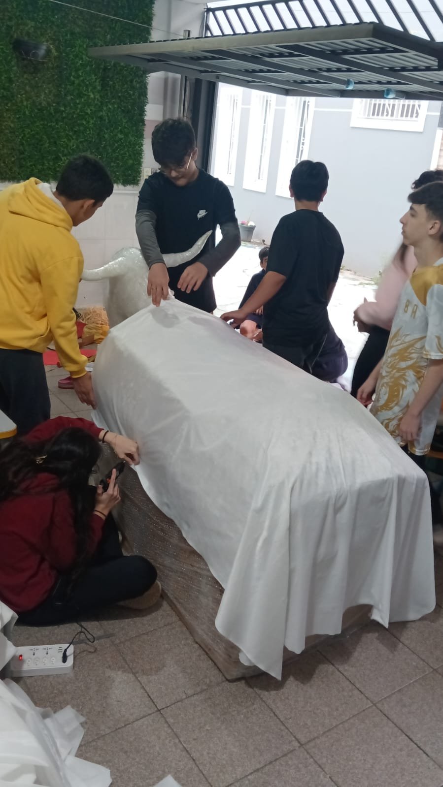 Alunos vestindo o boi com tecido branco